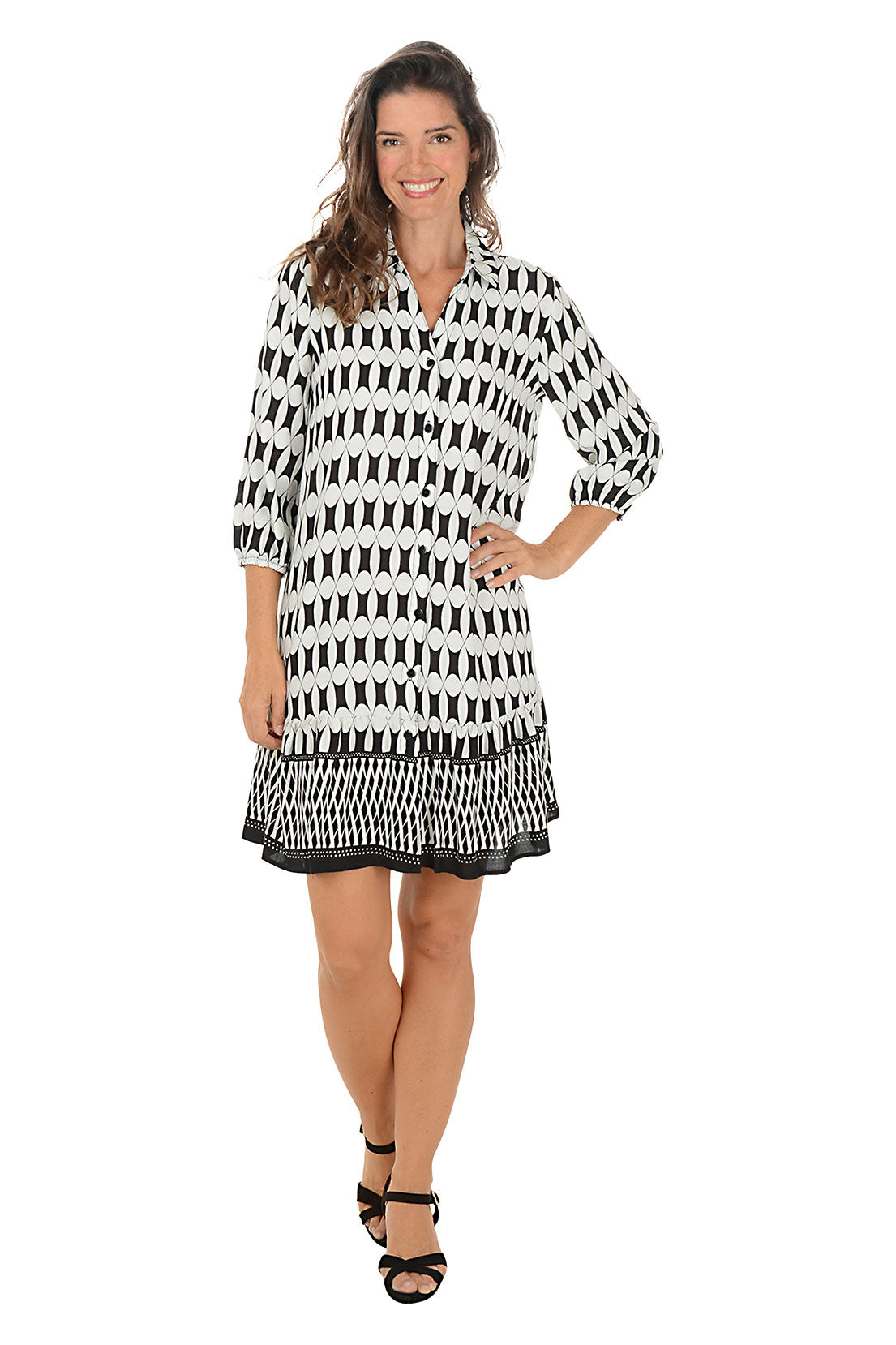 Woman wearing a 3/4 sleeved black and white patterned dress on a white background.
