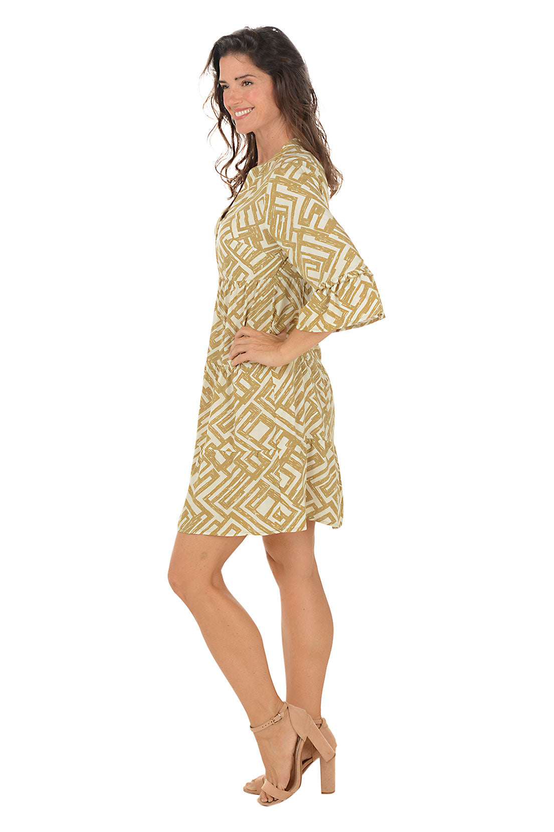 Woman wearing a gold and white patterned dress on a white background. Side shot.