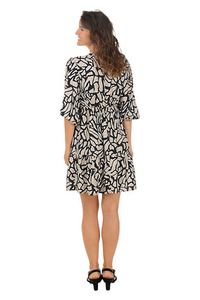Woman wearing a black and khaki 3/4 sleeve crackle patterned dress on a white background. Back shot.