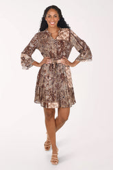 A woman modeling a brown and beige patterned mini dress with three-quarter bell sleeves and a tie waist, posed against a solid white studio background.