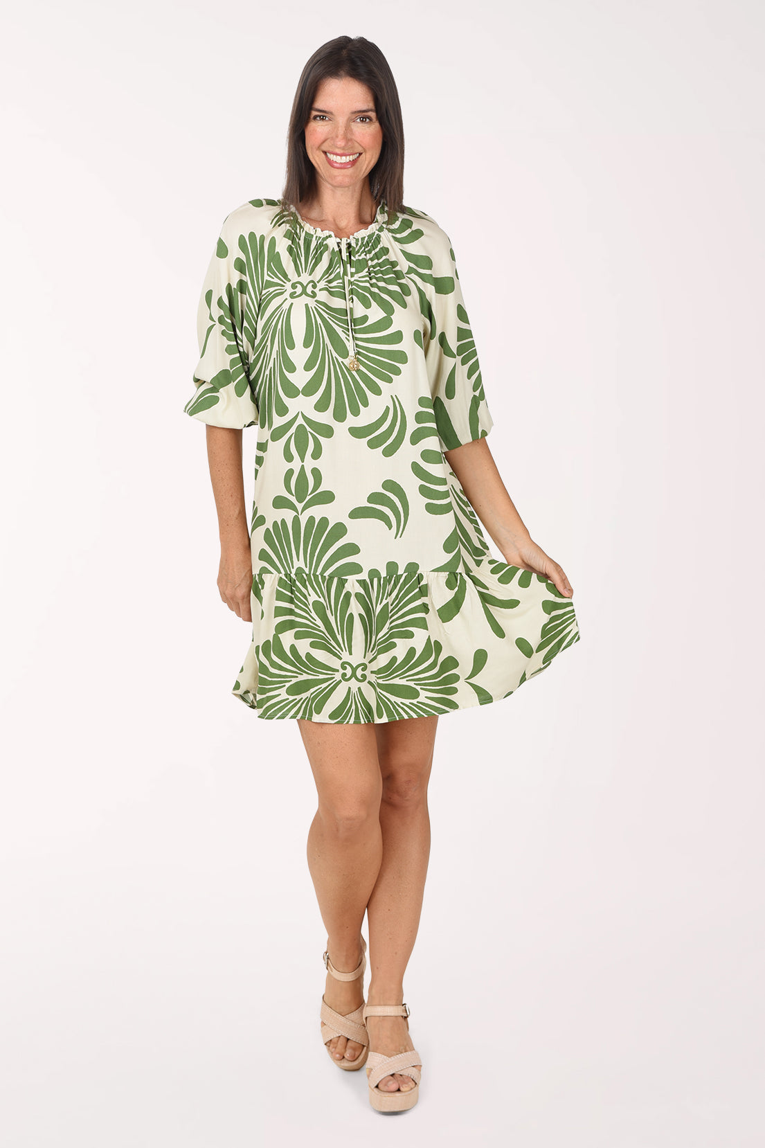 Model wearing the Mlle Gabrielle La Palma Drop Waist Dress, a cream dress with a bold green palm motif and elbow sleeves, front view