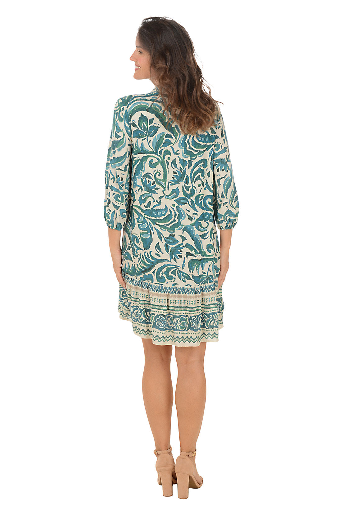 Woman wearing a 3/4 sleeve damask patterned dress in green and white on a white background. Back shot.