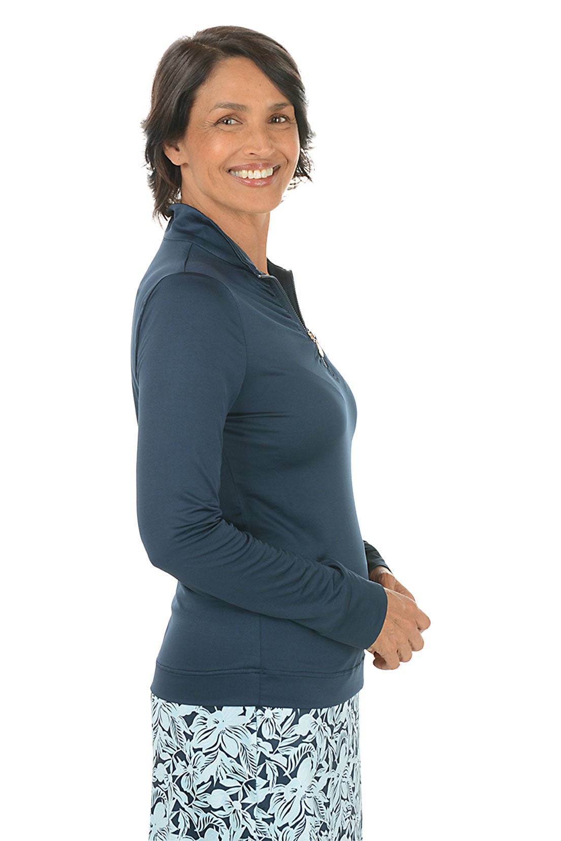 Woman wearing a navy long-sleeve top with a floral skirt on a white background. Side shot.