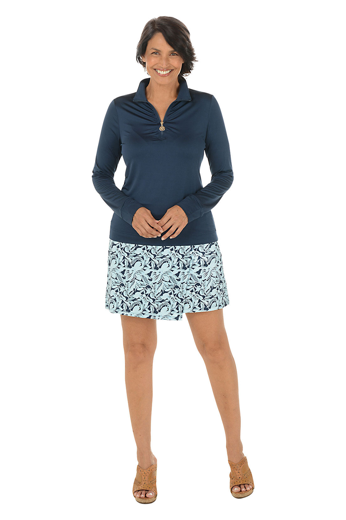 Woman wearing a navy long-sleeve top and patterned skirt on a white background