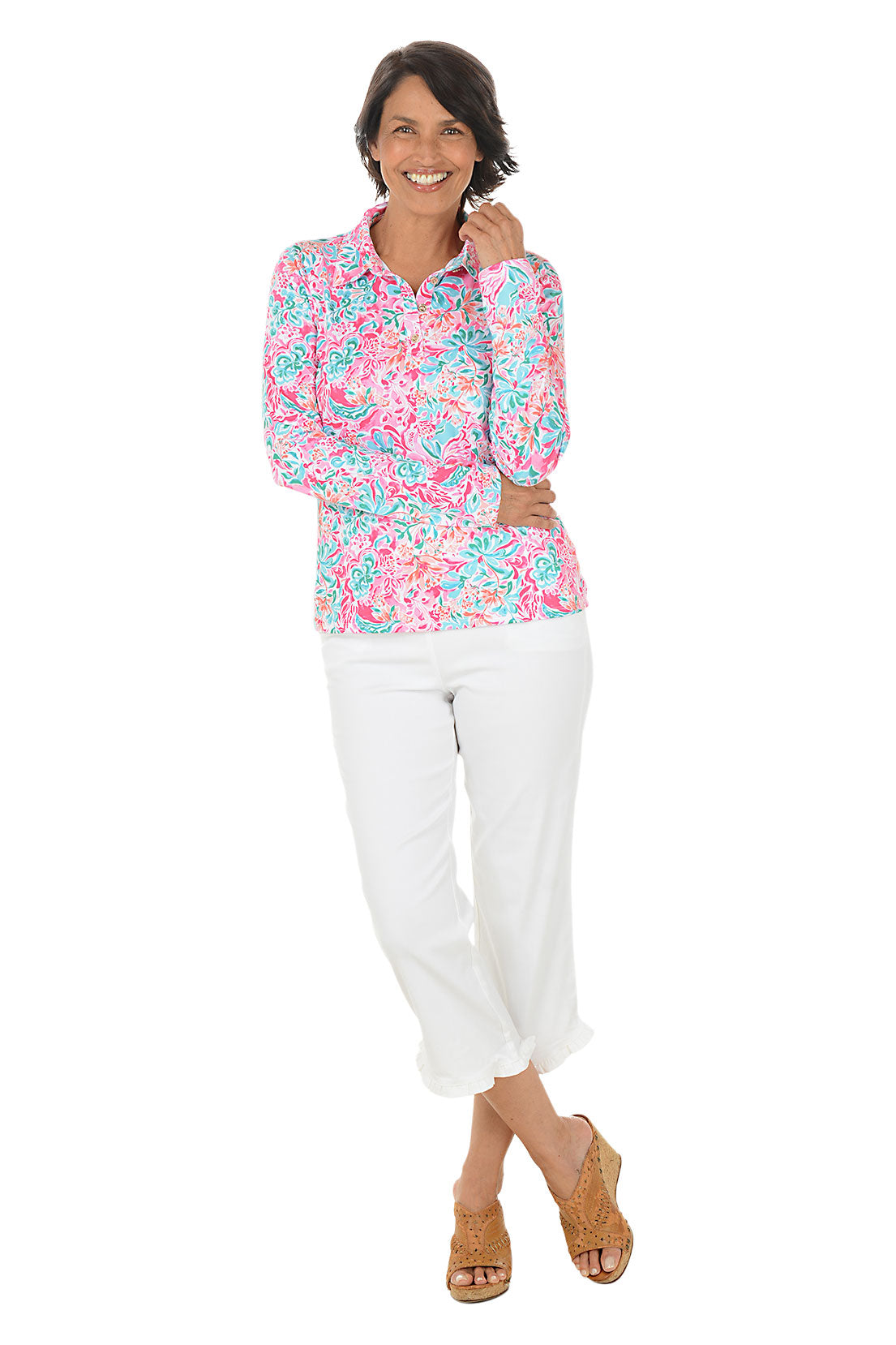 Woman wearing a colorful floral blouse and white pants on a white background