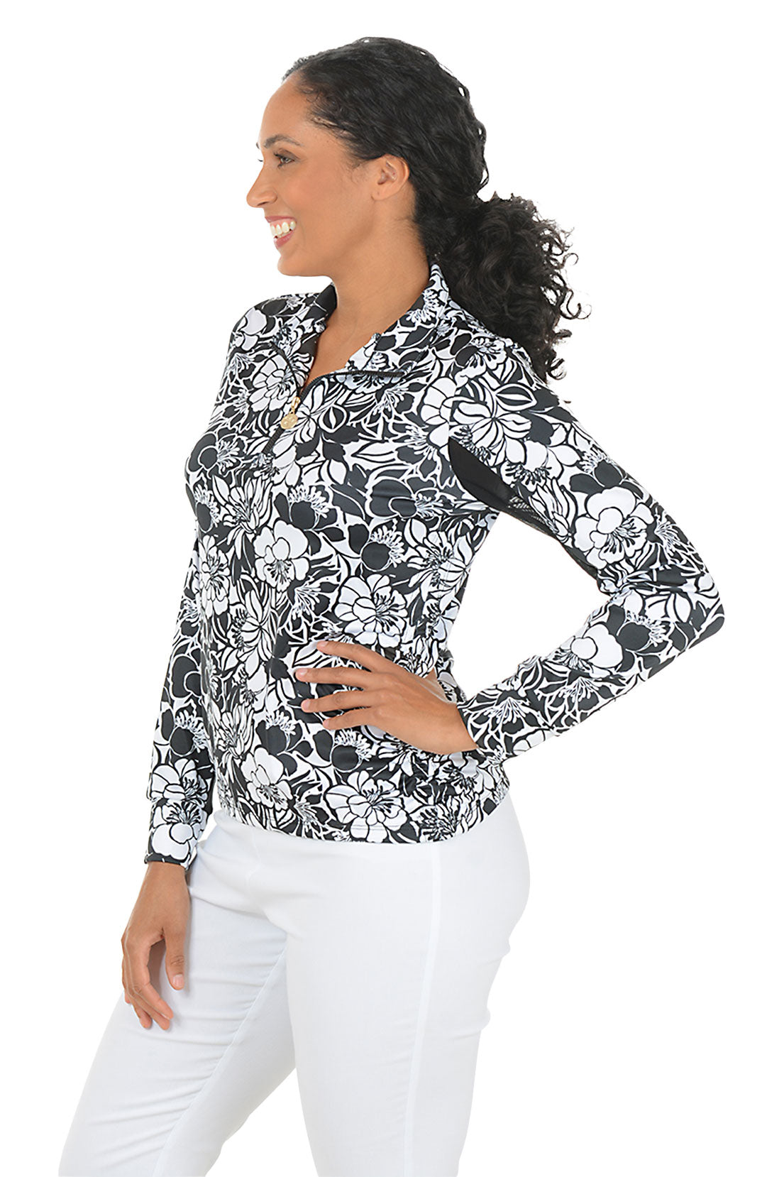 Woman wearing a black and white floral blouse with a white background. Side shot.