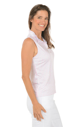 Woman wearing a sleeveless patterned top and white pants on a white background. Side shot.
