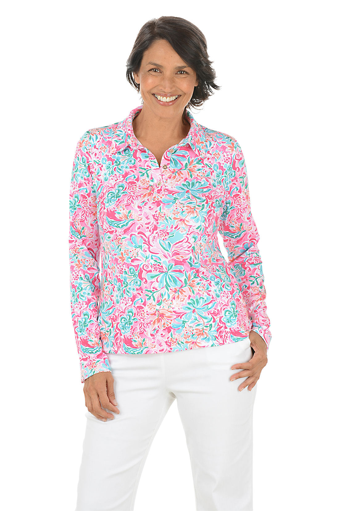 Woman wearing a colorful floral blouse with white pants on a white background.