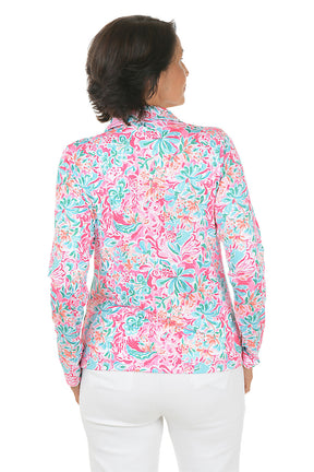 Woman wearing a colorful floral blouse with white pants on a white background. Back shot.
