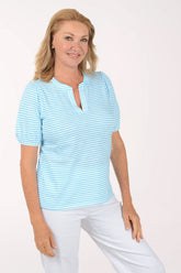 Woman wearing a light blue striped shirt and white pants on a white background