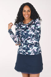 Woman wearing a floral long-sleeve top and navy skirt on a white background