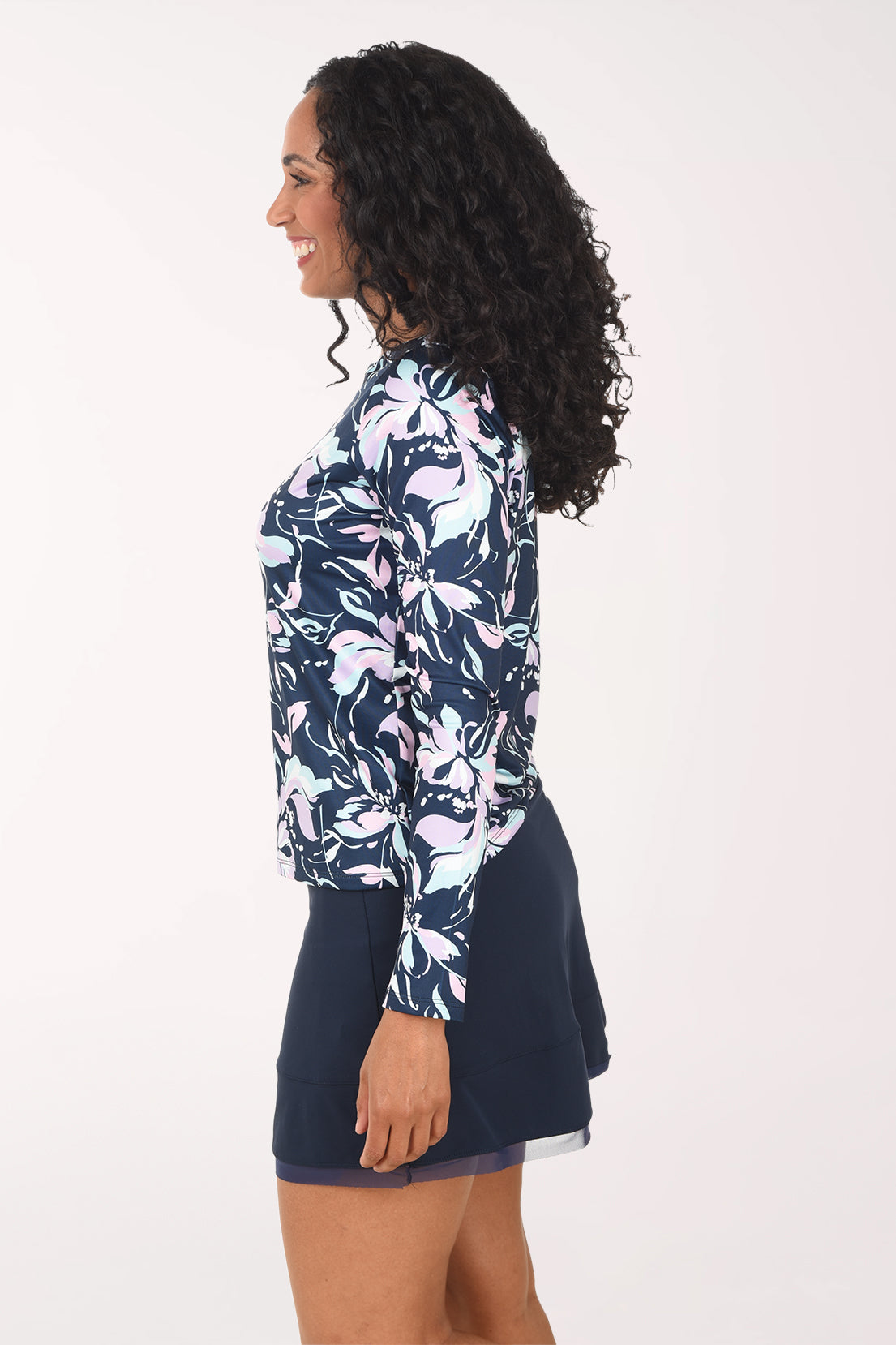 Woman wearing a floral long-sleeve top and navy skirt on a white background