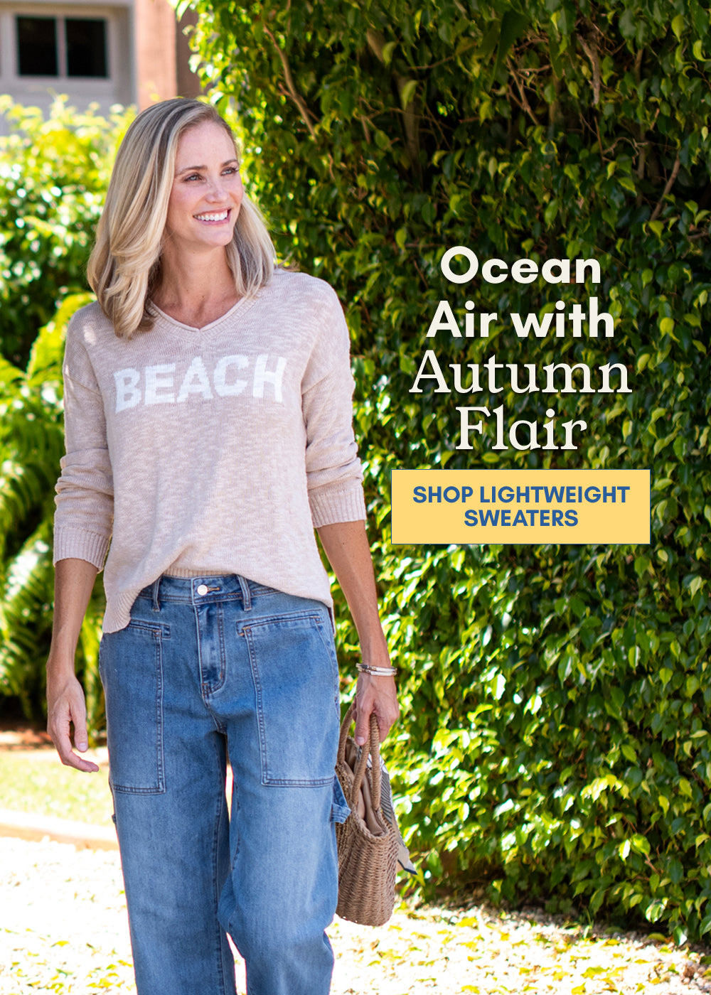 Woman modeling a beige lightweight BEACH sweater outdoors in a tropical setting.
