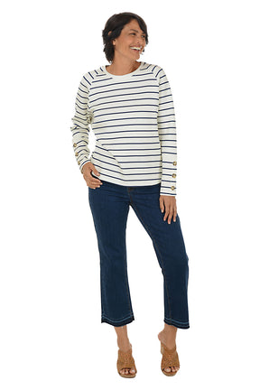 Woman wearing a striped long-sleeve top and dark blue jeans on a white background.