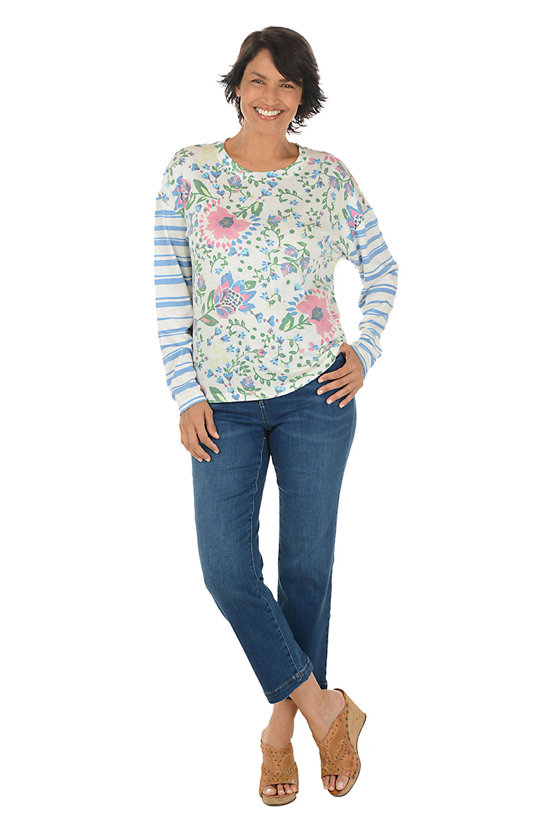 Woman wearing a floral long-sleeve top and blue jeans on a white background.