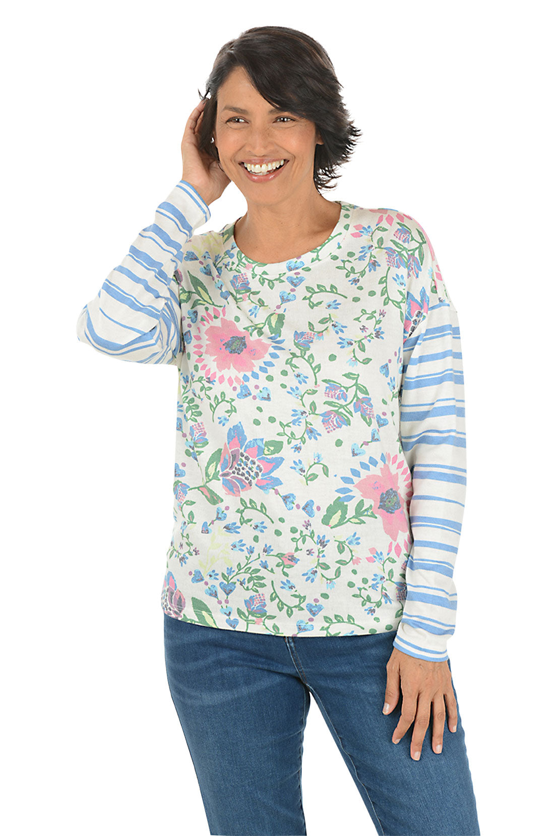 Woman wearing a floral long-sleeve shirt with blue jeans on a white background.