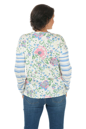 Woman wearing a floral long-sleeve shirt with blue jeans on a white background. Back shot.