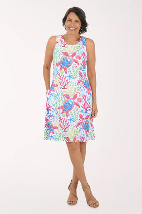Woman wearing a colorful dress with sea turtle and coral pattern on a white background