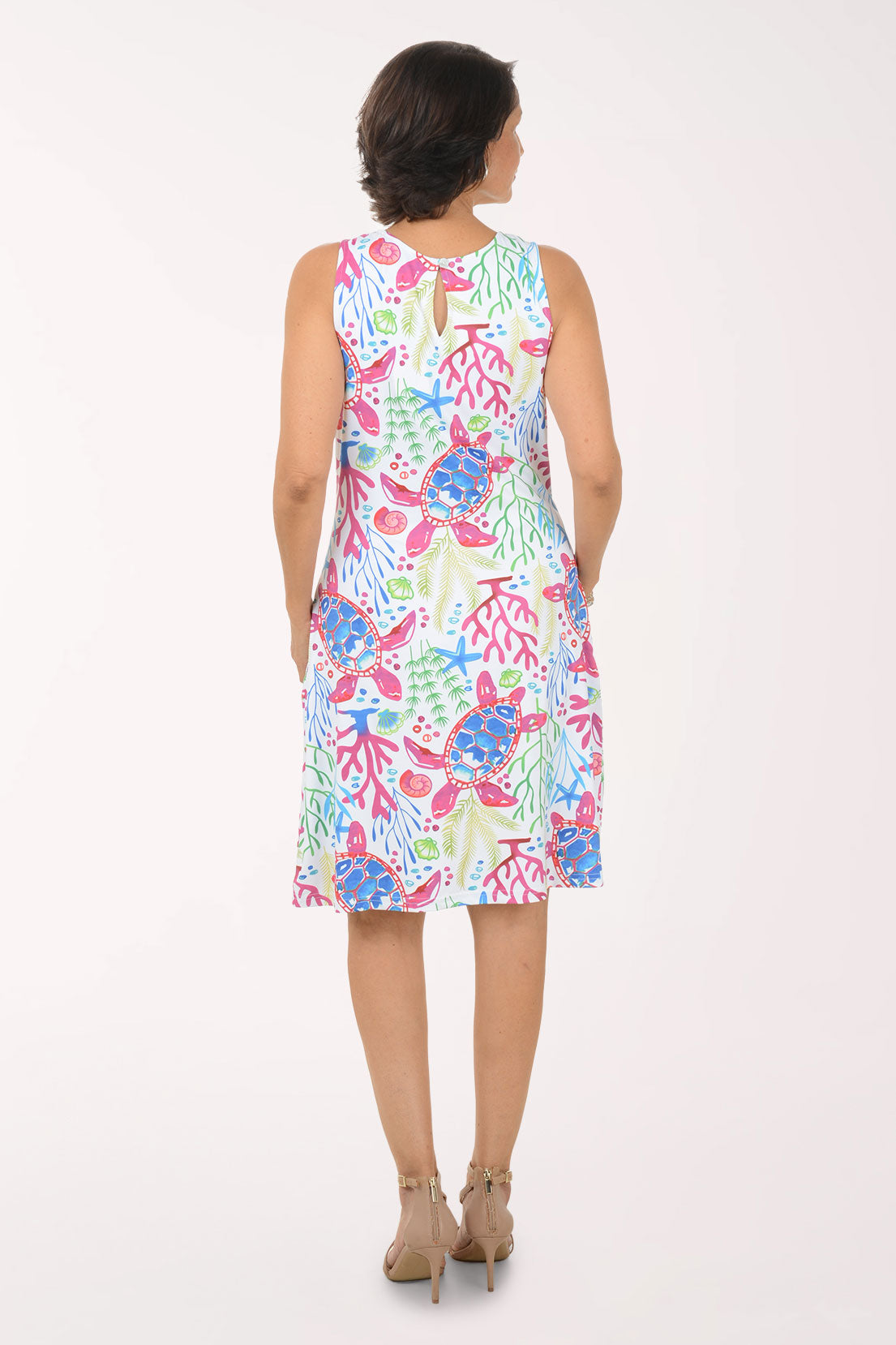 Woman wearing a colorful dress with sea turtle and coral pattern on a white background