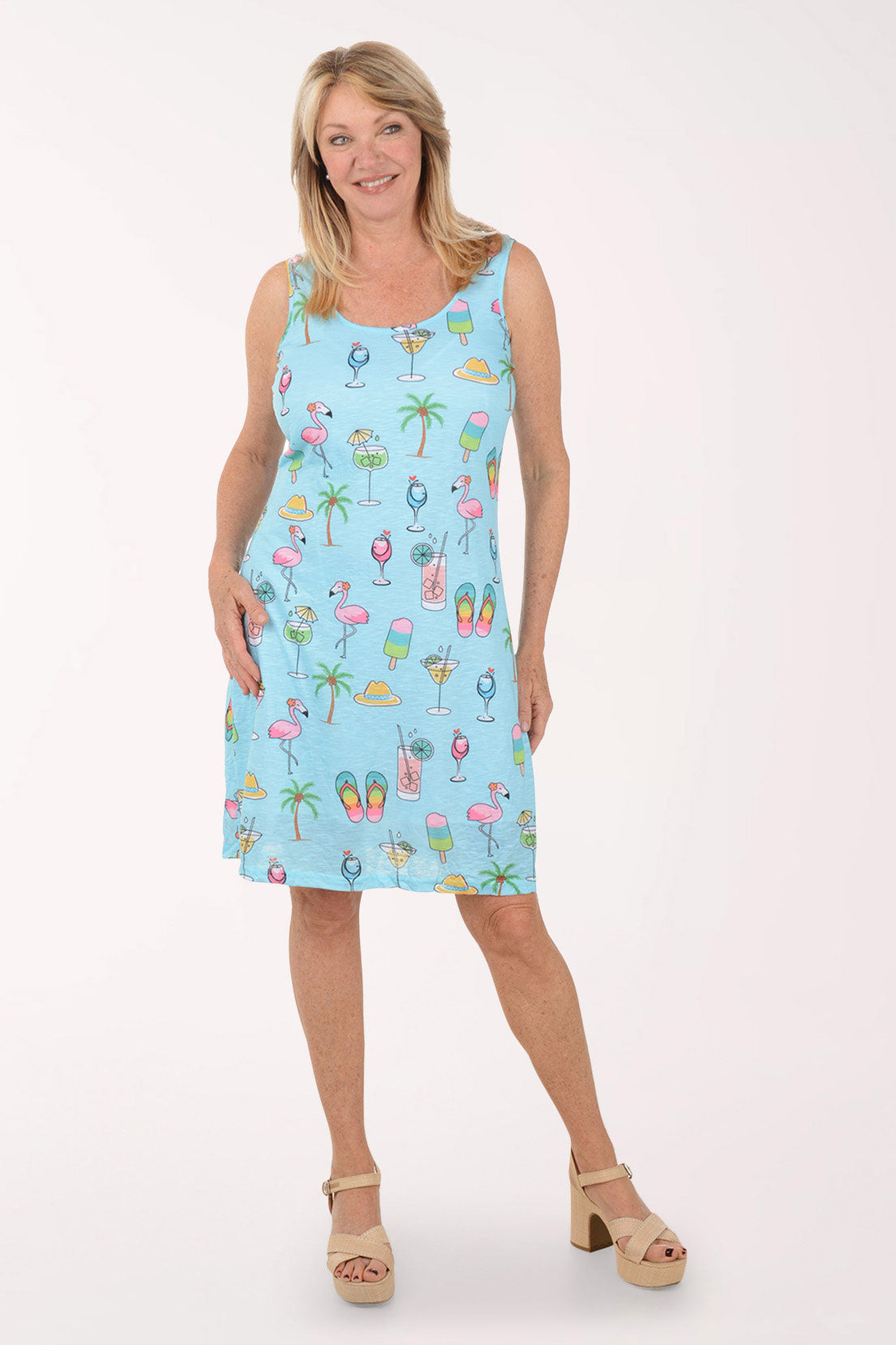 Woman wearing a light blue sleeveless dress with colorful summer-themed print on a white background