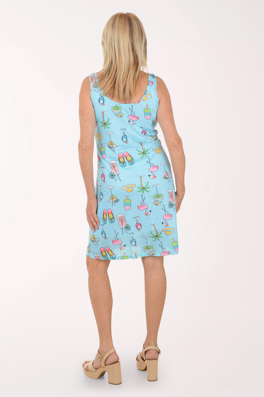 Woman wearing a light blue sleeveless dress with colorful summer-themed print on a white background