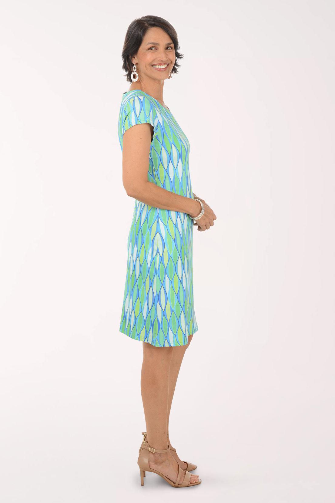Woman wearing a green and blue patterned dress on a white background