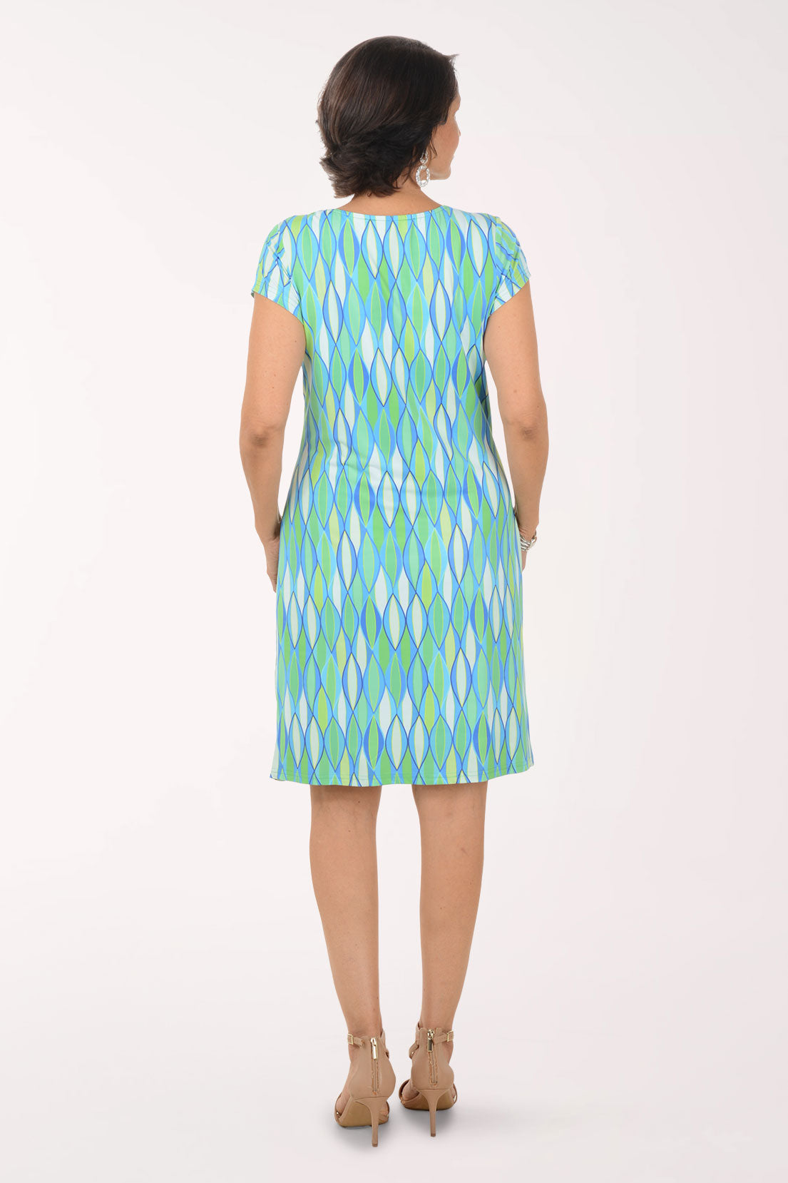 Woman wearing a green and blue patterned dress on a white background