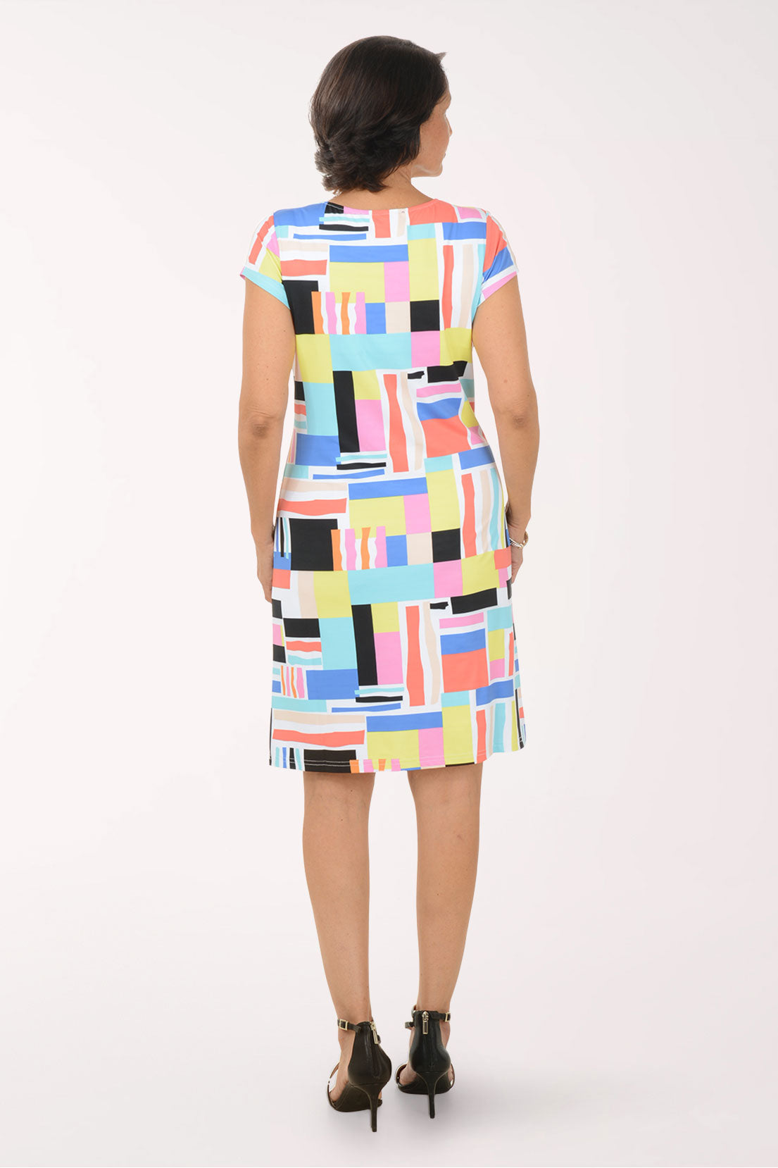 Woman wearing a colorful geometric patterned dress on a white background