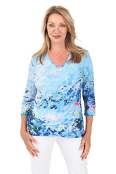 Woman wearing a blue floral long-sleeve top on a white background.