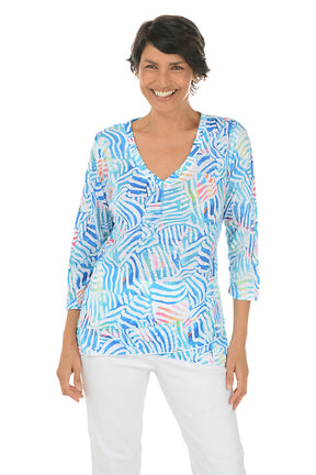 Woman wearing a colorful patterned blouse on a white background.