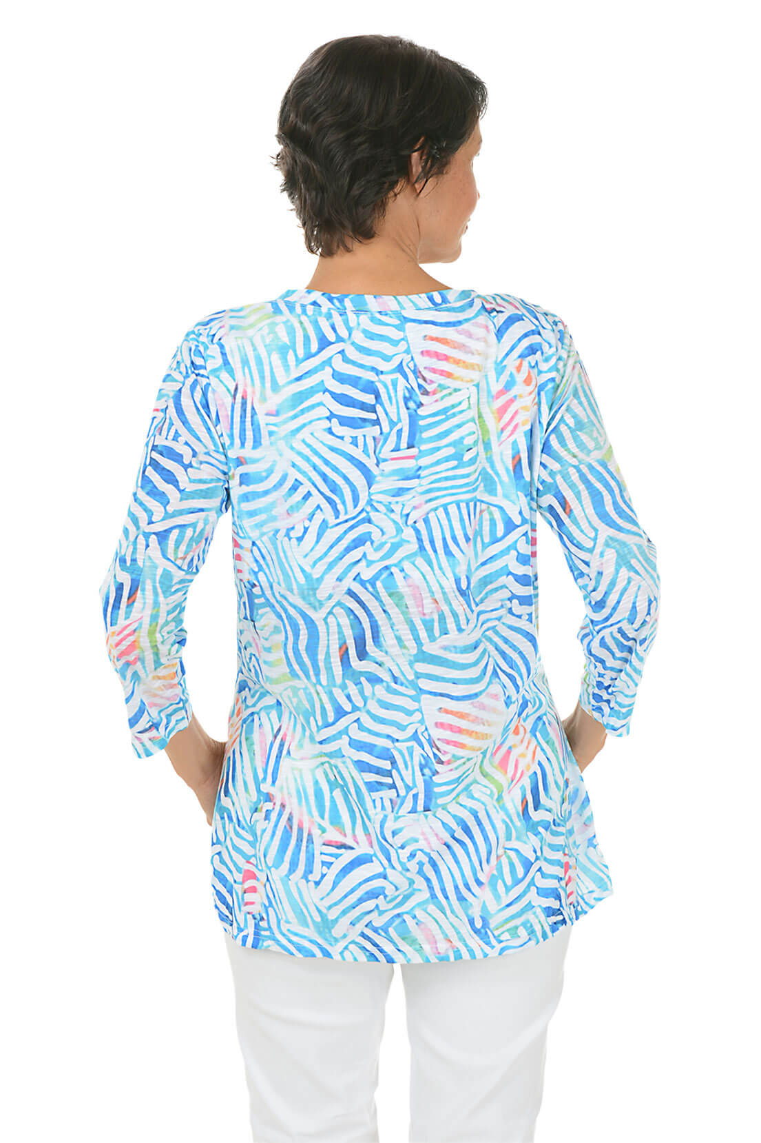 Woman wearing a colorful patterned blouse on a white background. Back shot.