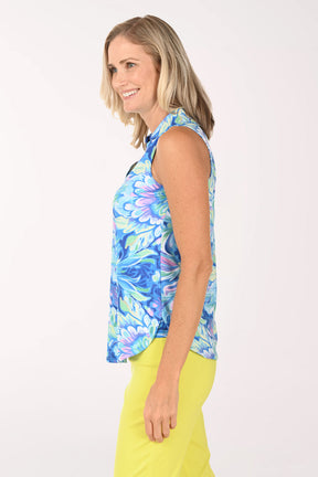 Woman wearing a colorful sleeveless top with floral pattern and yellow pants on a white background