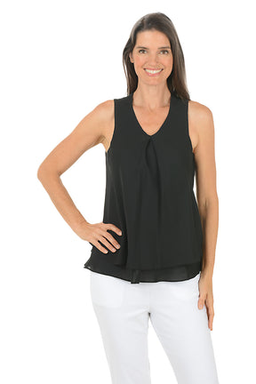 Woman wearing a black sleeveless top and white pants on a white background.