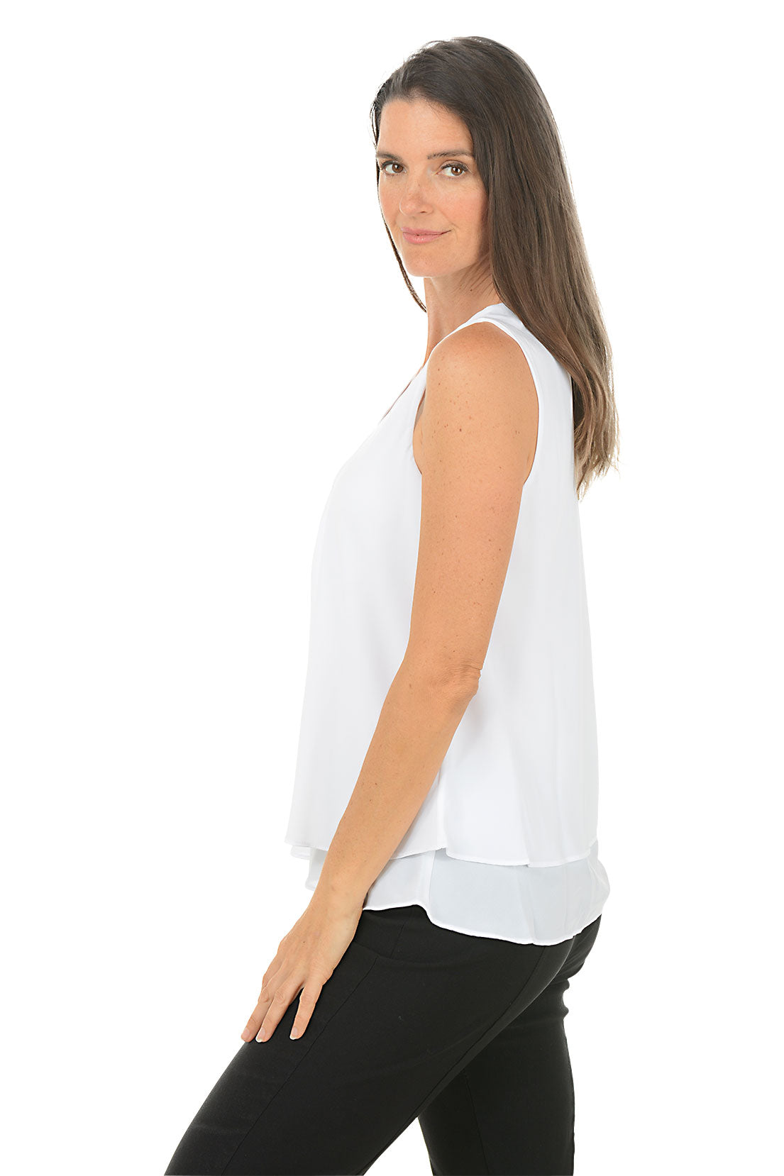 Woman wearing a white sleeveless top and black pants on a white background. Side shot.