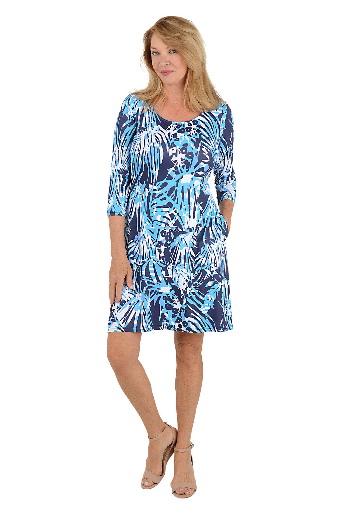 Woman wearing a blue and white abstract leaf patterned dress on a white background.