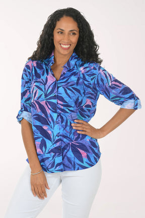 Woman wearing a colorful floral shirt and white pants on a white background