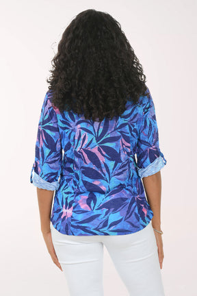 Woman wearing a colorful floral shirt and white pants on a white background