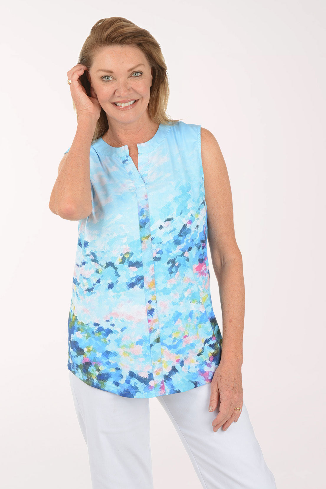 Woman wearing a sleeveless, light blue blouse with colorful abstract pattern on a white background