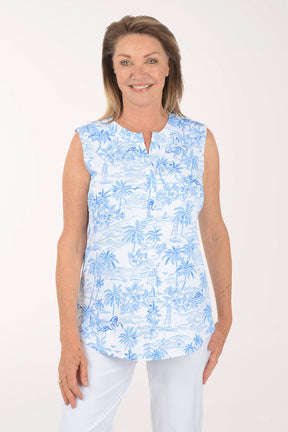 Woman wearing a blue floral sleeveless top and white pants on a white background