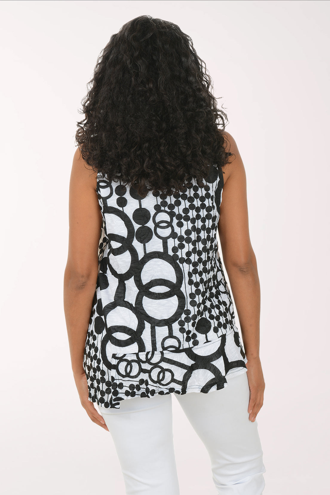 Woman wearing a sleeveless black and white patterned top on a white background