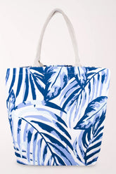 White cotton tote bag with an all-over palm leaf print in royal blue, periwinkle, and pale blue, with cream rope handles.