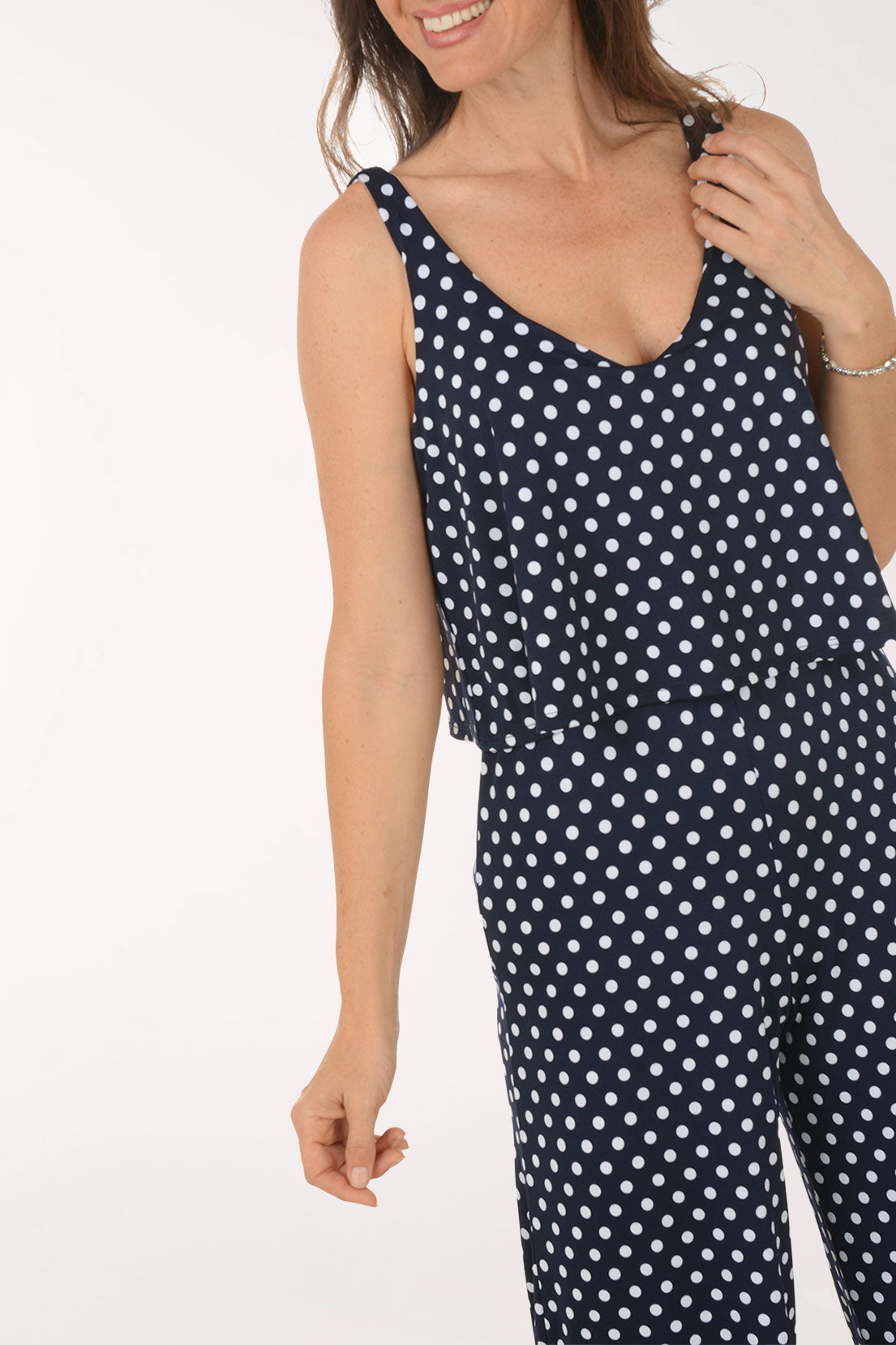 Woman wearing a navy blue jumpsuit with white polka dots on a white background