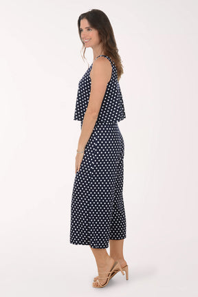 Woman wearing a navy blue jumpsuit with white polka dots on a white background