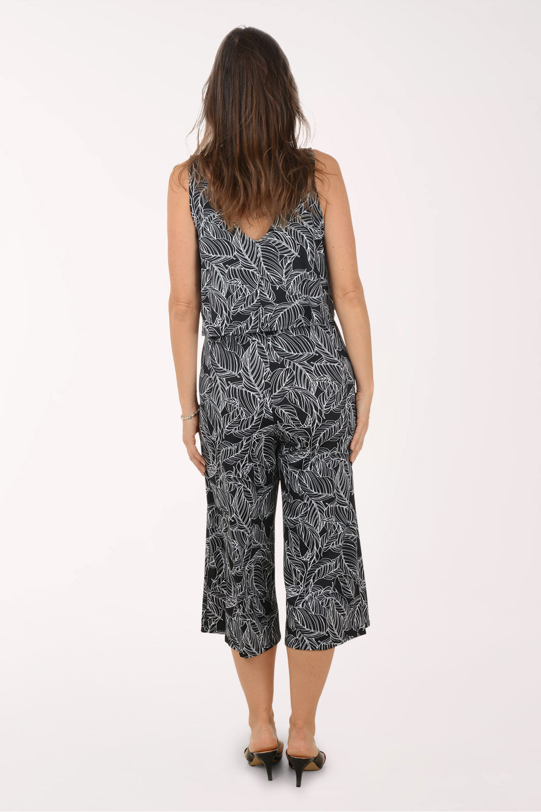 Woman wearing a black and white leaf-patterned jumpsuit on a white background