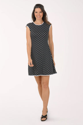 Woman wearing a black and white polka dot dress on a white background