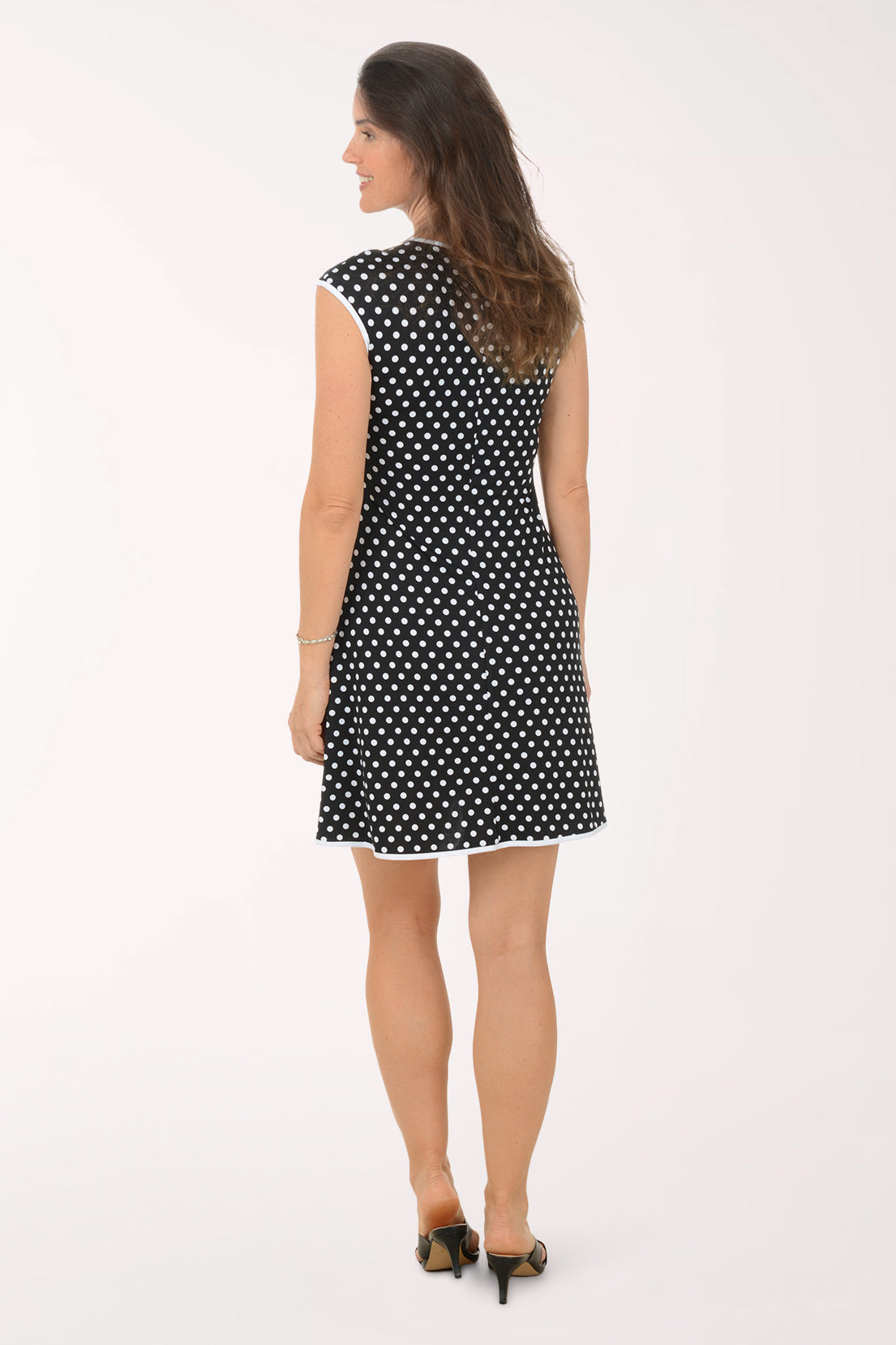 Woman wearing a black and white polka dot dress on a white background