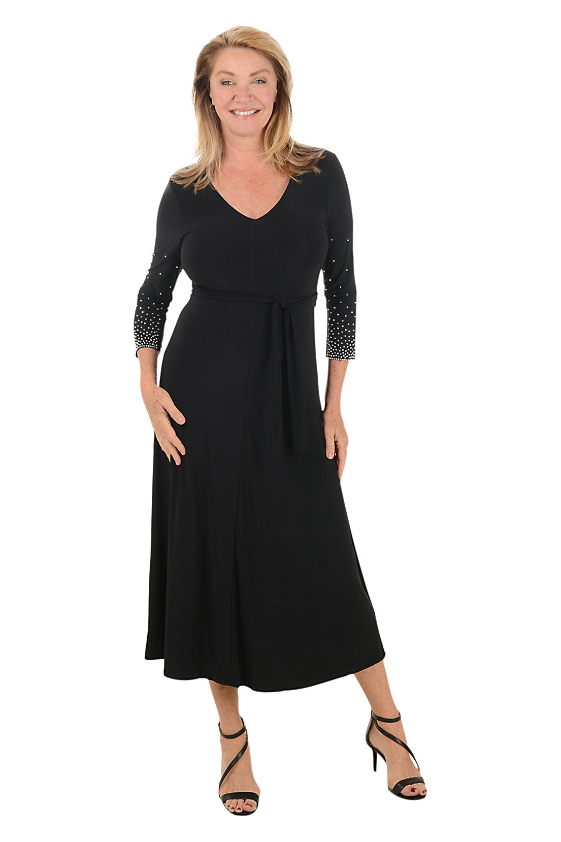 Woman wearing a black dress with embellished sleeves on a white background.