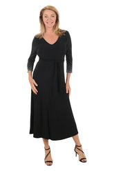 Woman wearing a black dress with embellished sleeves on a white background.