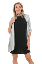 Woman wearing a black dress with a light gray cardigan on a white background.