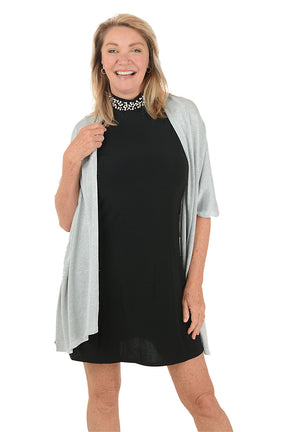 Woman wearing a black dress with a light gray cardigan on a white background.